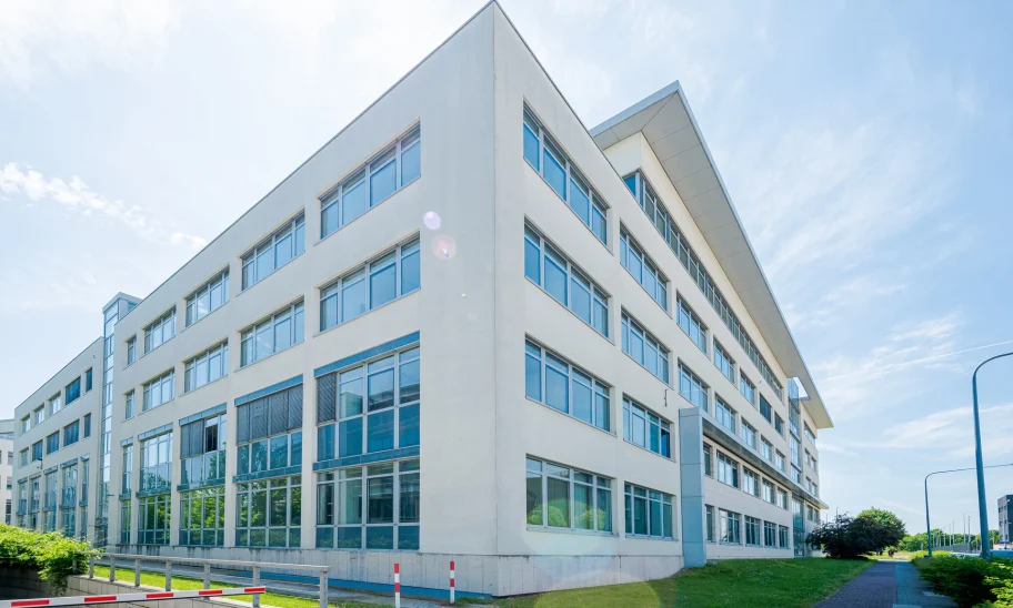 Eckansicht eines modernen Bürogebäudes mit Glasfassade und städtischer Umgebung.