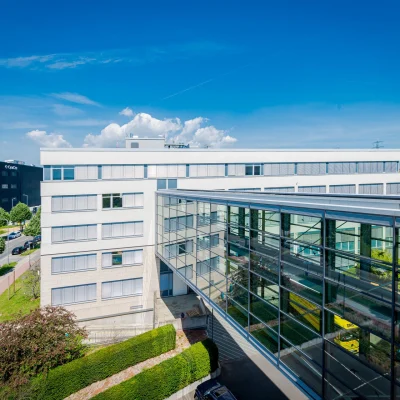 Moderne Dachterrasse des Bürogebäudes Tricubes in Frankfurt mit Glasfassade und Weitblick.