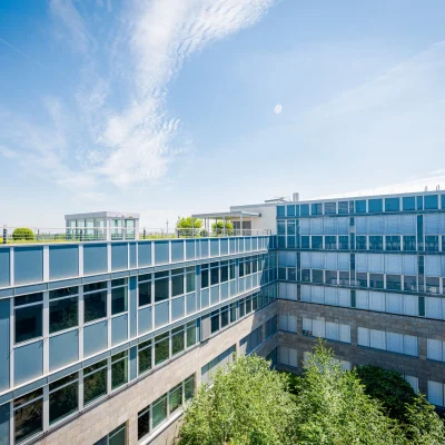 Blick auf eine moderne Dachterrasse mit Stadtpanorama und umliegendem Gebäudekomplex.