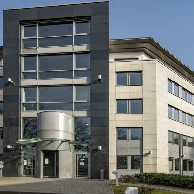 Abgebildet ist die linke Außenansicht eines Bürogebäudes mit Haupteingang und Vorplatz in Bonn.