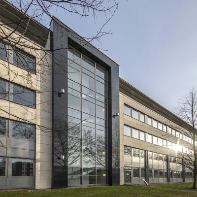 Das Bild zeigt die straßenseitige Perspektive eines mehrteiligen Büroensembles mit durchgängiger Fensterfassade.