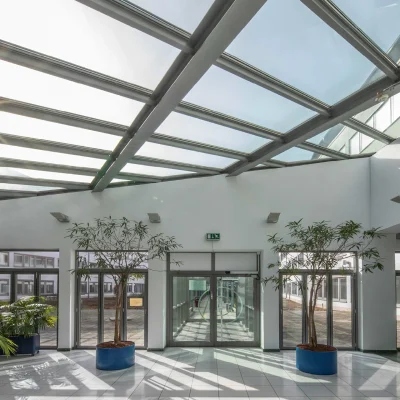 Das Bild zeigt die helle Lobby eines Bürogebäudes mit Glasdach und bepflanztem Eingangsbereich in Bonn.