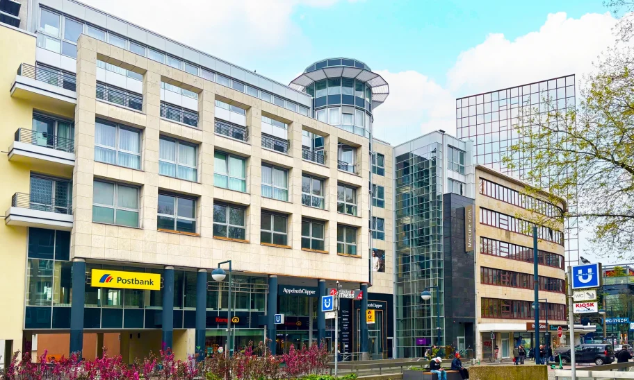 Das Bild zeigt die Frontansicht des Westfalenforums Dortmund mit Geschäften, Postbank, Fitnessstudio und moderner Glasarchitektur.