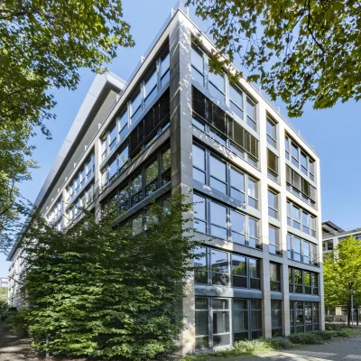 Das Bild zeigt ein modernes Bürogebäude mit Glasfassade und mehreren Etagen.