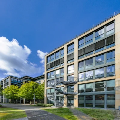 Das Bild zeigt ein modernes Bürogebäude mit Mietflächen und Arbeitsplätzen im Grünen.