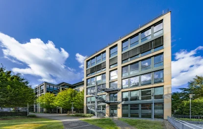 Das Bild zeigt ein modernes Bürogebäude mit Mietflächen und Arbeitsplätzen im Grünen.