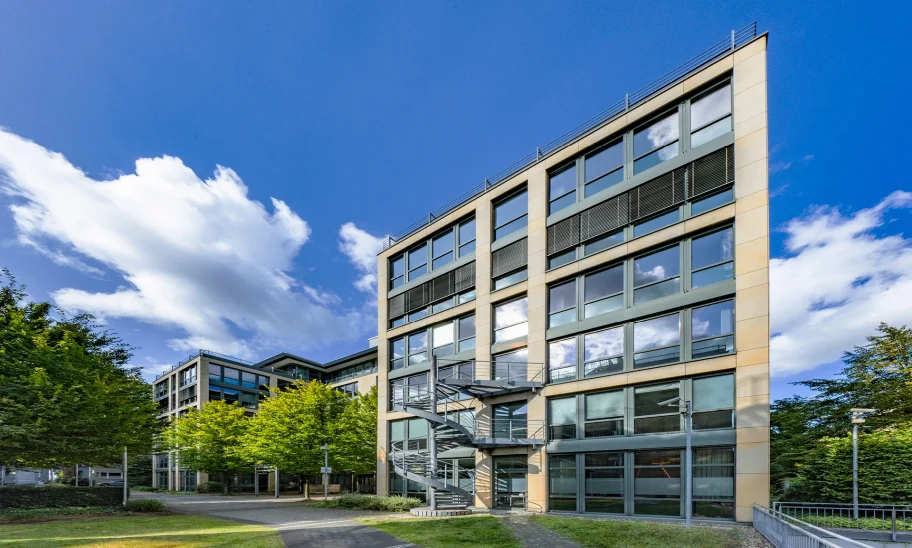 Das Bild zeigt ein modernes Bürogebäude mit Mietflächen und Arbeitsplätzen im Grünen.