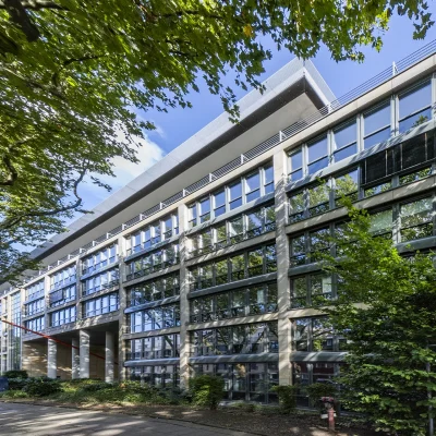 Das Bild zeigt die Außenansicht eines modernen Bürokomplexes mit großen Fensterfronten.