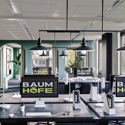 Das Bild zeigt einen stilvoll eingerichteten Co-Working-Bereich mit Schreibtischen und Computern.