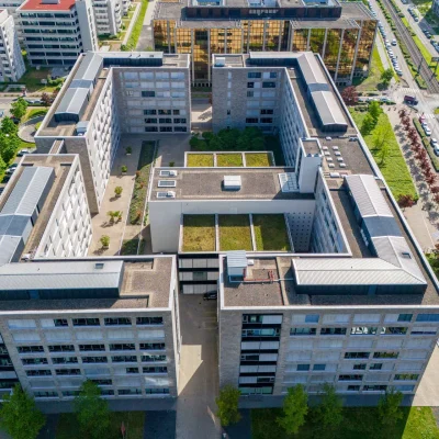 Ein Bürohaus an der Lyoner Straße in Frankfurt ist aus der Vogelperspektive mit begrünten Dachflächen und Innenhof sichtbar.