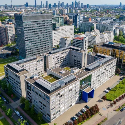 Das Luftbild zeigt einen großen Bürokomplex in Frankfurt mit Blick auf die Skyline und die umliegenden Hochhäuser.