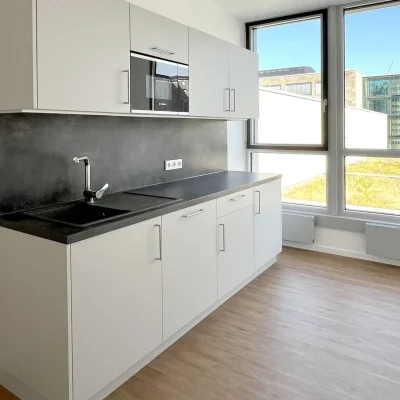 Eine moderne Büroküche mit großer Sitzgruppe und Panoramafenster bietet einen hellen Gemeinschaftsbereich in Frankfurt.