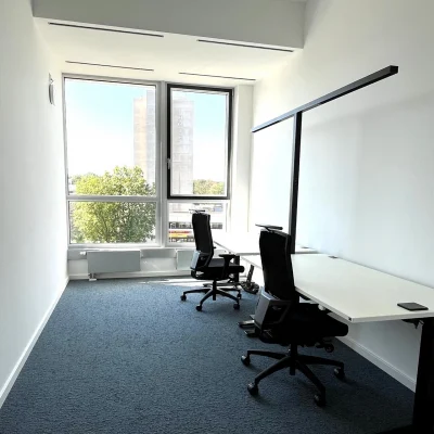 Ein helles Doppelbüro in Frankfurt mit zwei Arbeitsplätzen und großen Fenstern sorgt für eine freundliche Arbeitsatmosphäre.