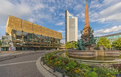 Das Bild zeigt das City-Hochhaus Leipzig am Augustusplatz mit Brunnen und Blumenbeet im Vordergrund.
