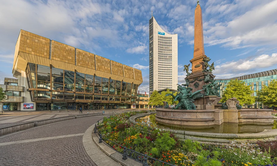 Das Bild zeigt das City-Hochhaus Leipzig am Augustusplatz mit Brunnen und Blumenbeet im Vordergrund.