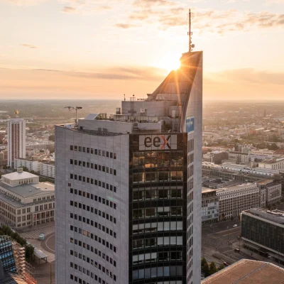 Das Bild zeigt das City-Hochhaus Leipzig bei Sonnenaufgang im Panorama über die Innenstadt.