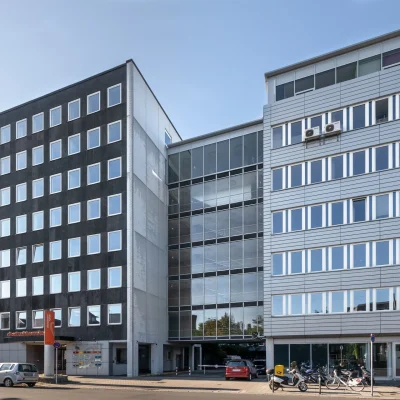 Ein moderner Bürokomplex mit Glasfassade und klarer Architektur an einer Straße.