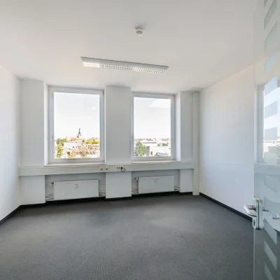Ein leerstehendes Büro mit großem Fenster, Stadtblick und weißen Wänden.