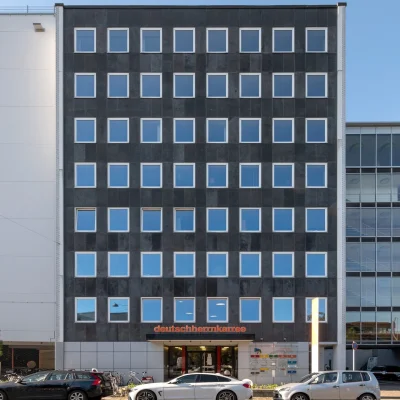 Ein moderner Bürokomplex mit Glasfassade und klarer Architektur an einer Straße.