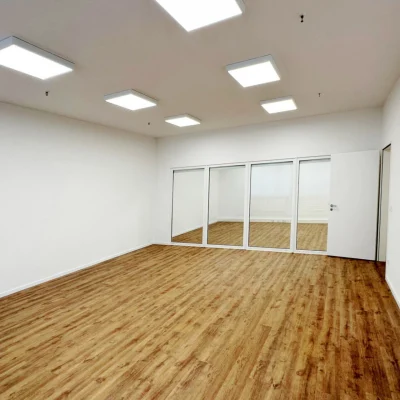 Das Bild zeigt einen renovierten Büroraum mit LED-Beleuchtung, Parkettboden und verglaster Trennwand.