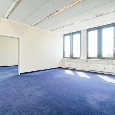 Abgebildet ist eine Büroeinheit mit Teppichboden, großer Fensterfront und heller Lichtdurchflutung.