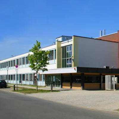Gezeigt wird ein Bürogebäude im Gewerbepark mit Straßenansicht, Parkanlage und weitläufigem Gebäudekomplex.