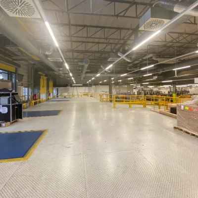 Das Bild zeigt eine große Industriehalle mit Verladerampe und Lagerfläche für die Paketlogistik.