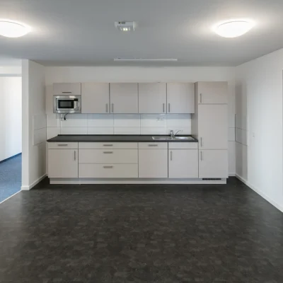 Moderne Teeküche in einer Büroeinheit mit Einbauschränken, Spüle und Mikrowelle.