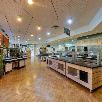 Moderner Kantinenbereich mit Buffetstrecke, Holzboden und dekorativen Pflanzen in einem Bürogebäude.