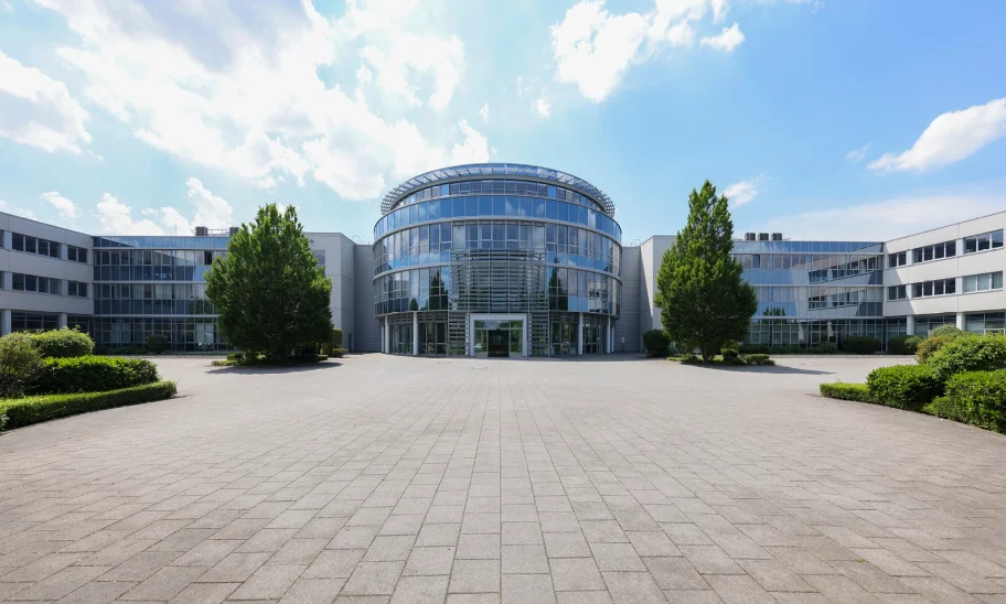 Das Bild zeigt den Haupteingang des Kerpen Techparks mit runder Glasfassade und umliegenden modernen Büroeinheiten.