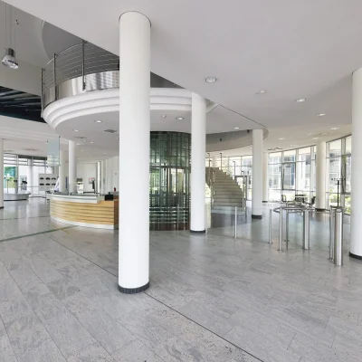 Das Bild zeigt die großzügige Empfangshalle eines modernen Bürogebäudes im Kerpen Techpark mit runder Rezeption und Glasaufzug.