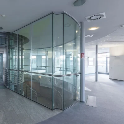Das Bild zeigt einen verglasten Fahrstuhl im Inneren eines modernen Bürogebäudes im Kerpen Techpark mit umlaufenden Glaswänden.