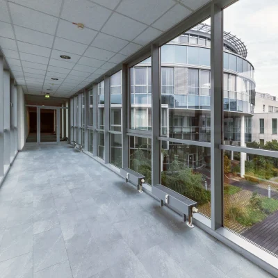 Das Bild zeigt einen lichtdurchfluteten Flur mit Glaswänden im Verbindungsbau des Kerpen Techparks mit Blick auf den begrünten Innenhof.