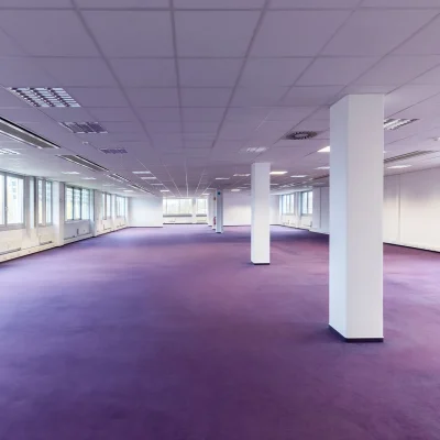 Das Bild zeigt eine große, leere Bürofläche im Kerpen Techpark mit lila Teppichboden und vielen Fenstern für Tageslicht.