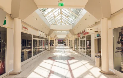 Das Bild zeigt eine lichtdurchflutete Einkaufspassage im Hansa-Centrum Krefeld mit leerstehenden Ladengeschäften und großem Glasdach.