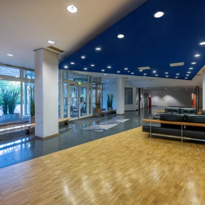 Empfangsbereich eines Bürogebäudes mit moderner Möblierung, Glasfront und Pflanzendekoration.