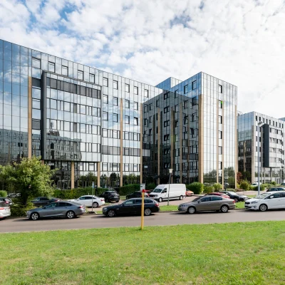 Die Aussenansicht von einem modernen Bürogebäude mit Parkplätzen und Eingangsbereich.