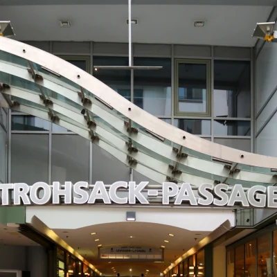 Das Bild zeigt die Außenansicht eines modernen Bürogebäudes mit Glasfassade im Leipziger Stadtzentrum, Teil der Strohsack-Passage mit Zugang zu Läden und Büros.