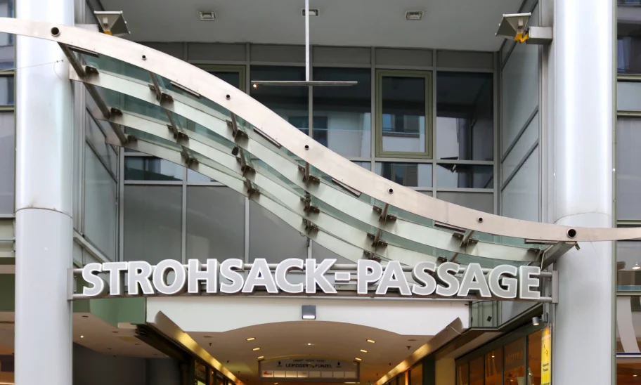 Das Bild zeigt die Außenansicht eines modernen Bürogebäudes mit Glasfassade im Leipziger Stadtzentrum, Teil der Strohsack-Passage mit Zugang zu Läden und Büros.