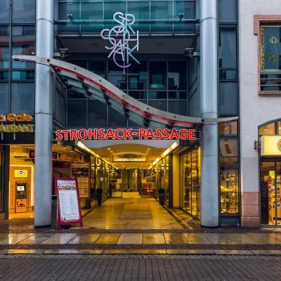 Der nächtlich beleuchtete Eingang der Strohsack-Passage in Leipzig von der Straße aus gesehen.