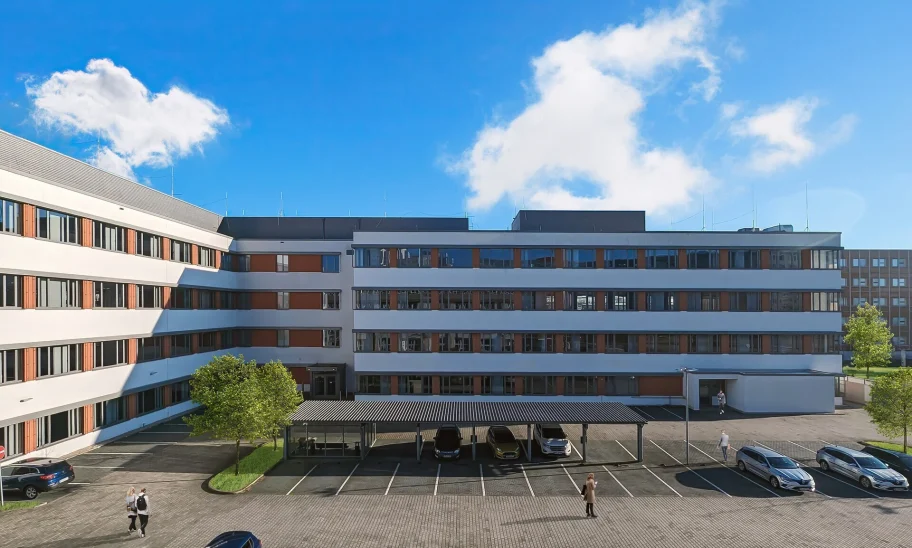 Abgebildet ist die Rückansicht eines Bürogebäudes in Frankfurt mit Parkplätzen und überdachten Stellplätzen.