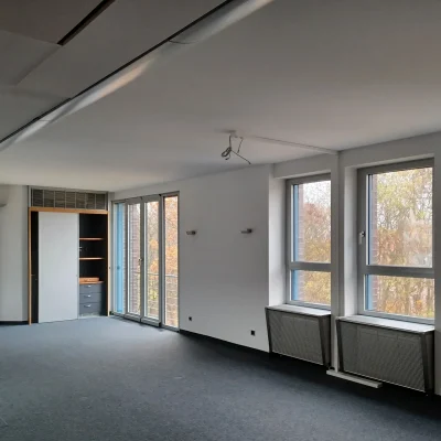 Ein leerstehendes Einzelbüro in Nürnberg mit Fensterfront, Teppichboden und integriertem Schrank.