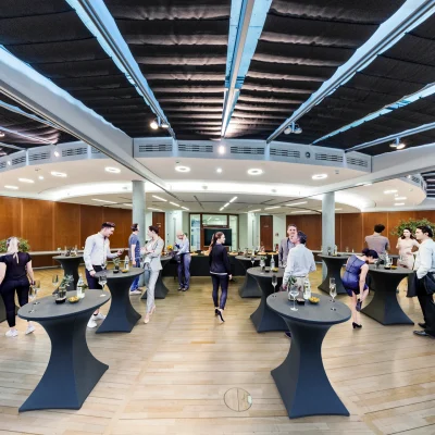 Mehrere Personen unterhalten sich bei einem Business-Event mit Stehtischen im Empfangsbereich eines Frankfurter Bürogebäudes.