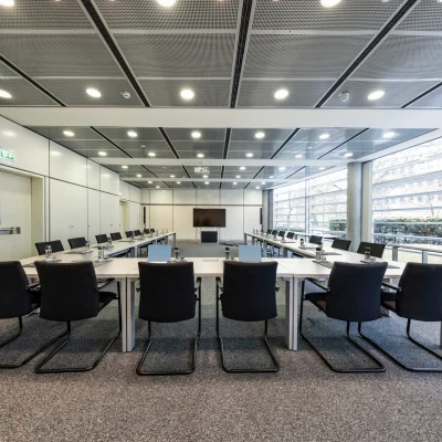 Ein heller Konferenzraum in Frankfurt mit moderner Sitzanordnung und großen Fensterfronten für viel Tageslicht.