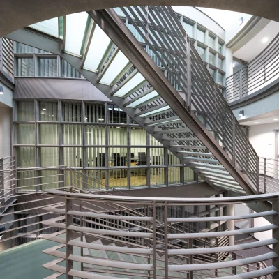 Ein offenes Treppenhaus mit Metallgeländer und Glasdach in einem Frankfurter Bürohaus mit Blick auf mehrere Büroetagen.