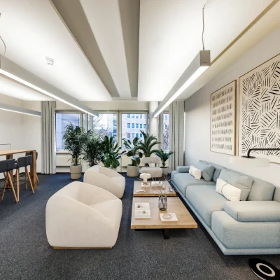 Ein ruhiger Lounge-Bereich mit modernen Möbeln, Pflanzen und großen Fenstern in einem Frankfurter Bürogebäude.
