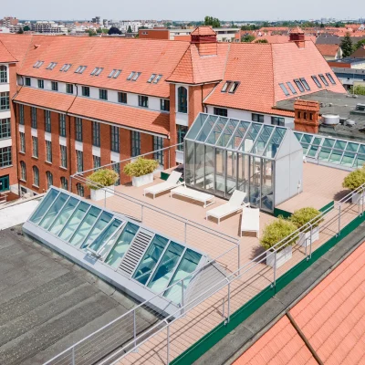 Das Bild zeigt eine moderne Dachterrasse mit Lounge-Möbeln und Ziegeldach mitten in der Stadt.
