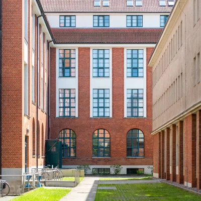 Das Bild zeigt einen begrünten Innenhof eines Bürogebäudes mit Backsteinfassade und Fahrradständern.