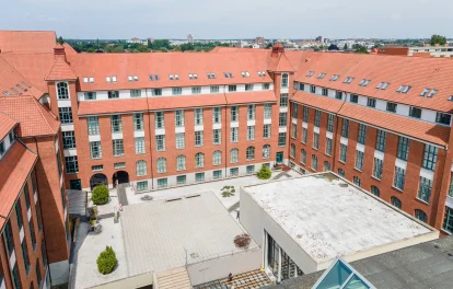 Das Bild zeigt einen Innenhof mit roten Backsteinbüros und umliegenden Bürogebäuden mit Ziegeldächern.