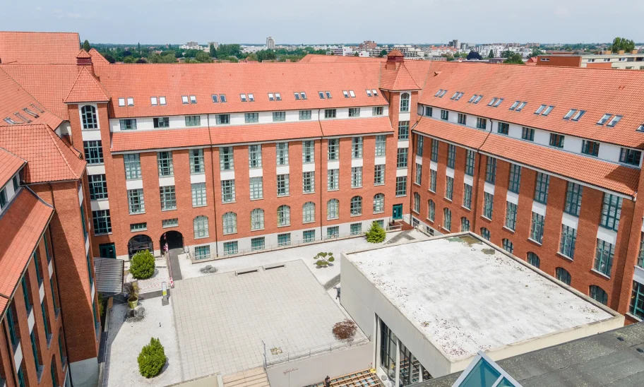 Das Bild zeigt einen Innenhof mit roten Backsteinbüros und umliegenden Bürogebäuden mit Ziegeldächern.